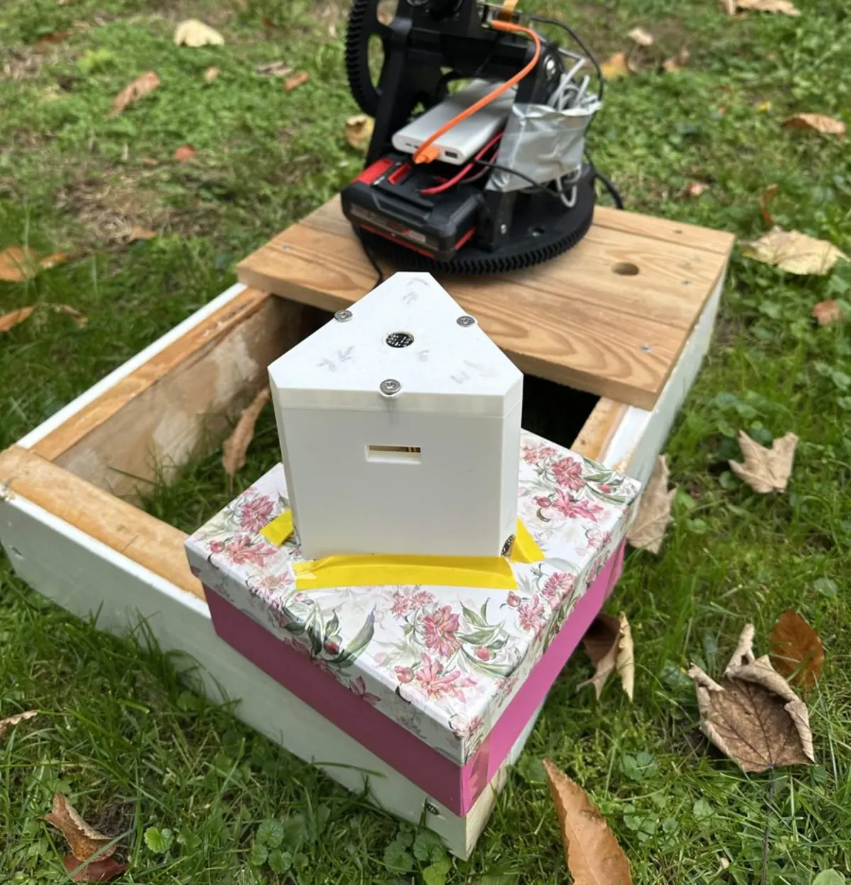 Pyramid-shaped listening unit with four microphones, turret v1 behind it, outdoors on grass
